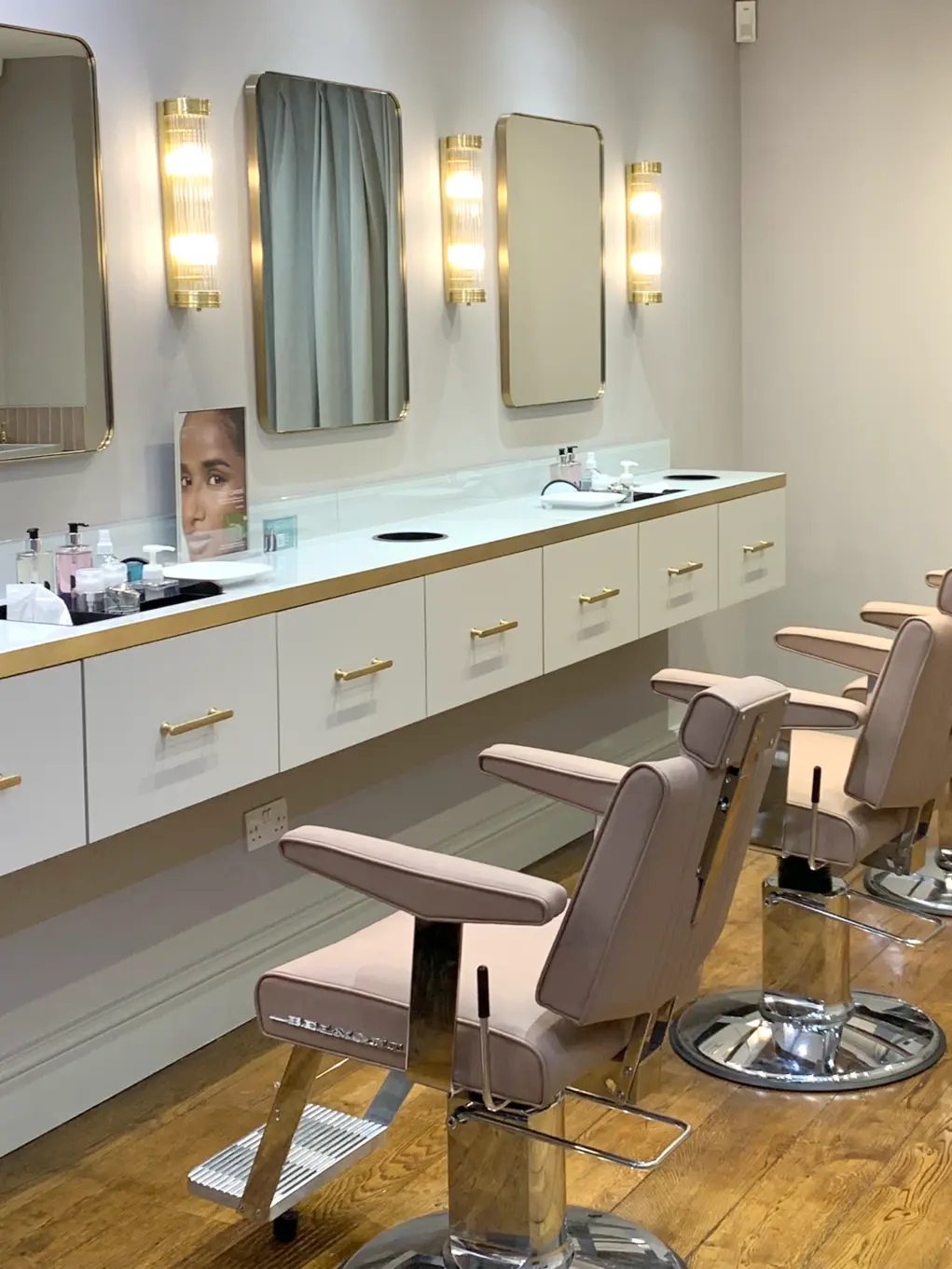 Interior of Blink Brow Bar with pink chairs, a white counter and mirrors