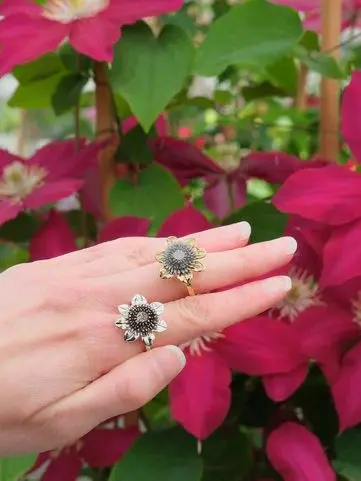 Hand with two rings with a backdrop of flowers
