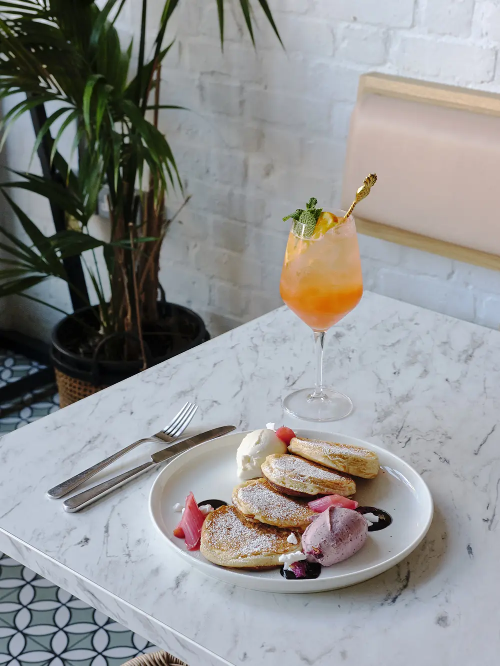 A plate of pancakes and a tropical drink in a cocktail glass with a straw