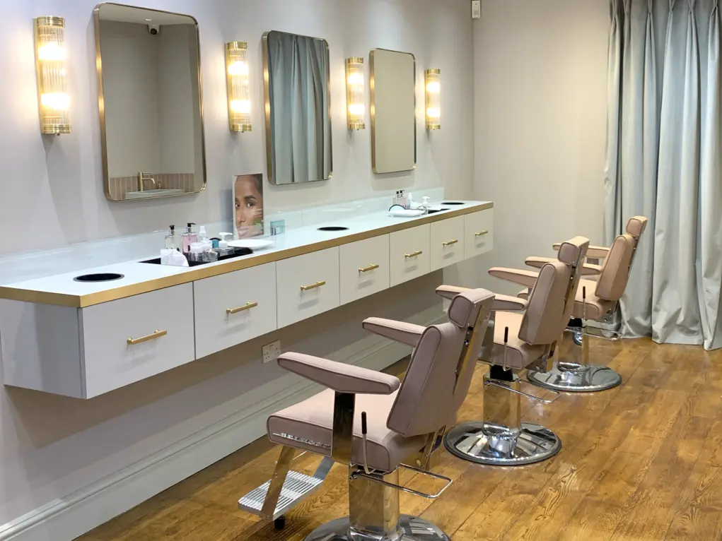 Interior of Blink Brow Bar with pink chairs, a white counter and mirrors